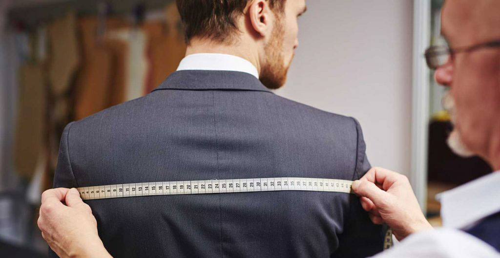 Vue en gros plan d'un mètre ruban de tailleur posé sur un tissu de costume haut de gamme, texture visible et lumière naturelle