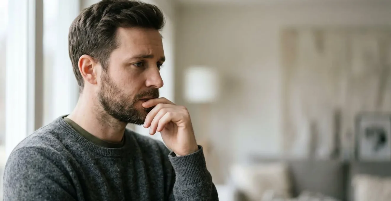 Homme en moment de réflexion face à un choix vestimentaire, expression concentrée et consciente
